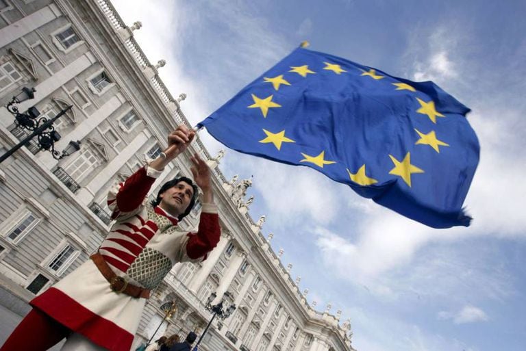 Um membro do grupo italiano "Sbandieratori dei Siena" enquanto sustenta uma bandeira da União Europeia em frente ao Palácio Real em Madri.