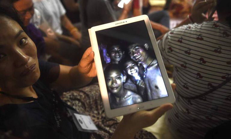 Uma familiar mostra uma foto de alguns dos desaparecidos tirada dentro da gruta pelas equipes de resgate nesta segunda-feira, na Tailândia.