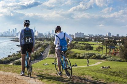 Dois ciclistas em Point Ormond, com o skyline de Melbourne ao fundo
