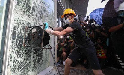 Manifestante tenta quebrar janela do Parlamento em Hong Kong, nesta segunda-feira.