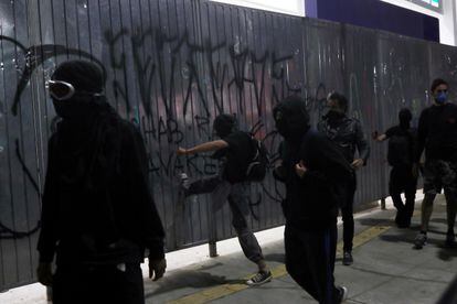 Manifestantes mascarados chutam portão de loja em São Paulo. 