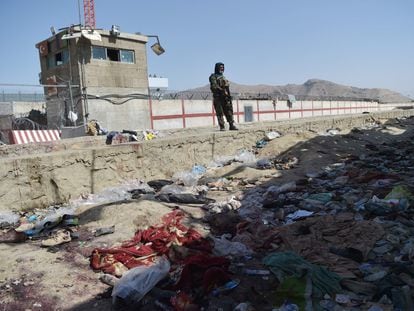Um talibã monta guarda nesta sexta-feira no local onde um homem-bomba se explodiu, próximo a um portão no aeroporto de Cabul na quinta-feira.