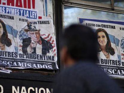 Um homem passa por cartazes que falam da crise argentina, em Buenos Aires.