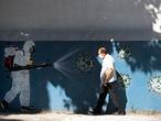 A man walks past a mural representing a worker in protective gear spraying disinfectant on a new coronavirus that has the face of Brazil's President Jair Bolsonaro painted on it, in Rio de Janeiro, Brazil, Monday, June 22, 2020. (AP Photo/Silvia Izquierdo)