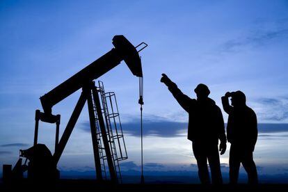 Dois trabalhadores observam um poço de extração de petróleo