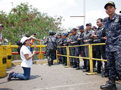 Uma seguidora de Juan Guaidó se ajoelha diante de agentes da Guarda Nacional Bolivariana.