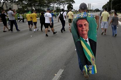 Manifestante carrega bandeira com imagem do presidente Jair Bolsonaro durante caravana em seu apoio em Brasília, no Primeiro de Maio.