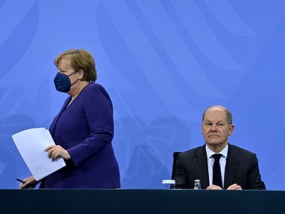A chanceler Angela Merkel chega à coletiva de imprensa para anunciar as novas restrições e senta-se ao lado de seu sucessor, Olaf Scholz, na quinta-feira em Berlim.