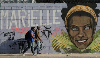 Dois transeúntes ante um grafiti de Marielle Franco, o vereador assassinada faz em um ano em Rio.
