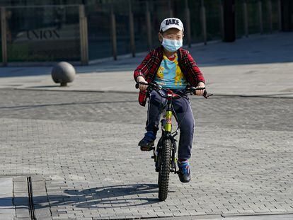 Menino anda de bicicleta com uma máscara em Pequim.