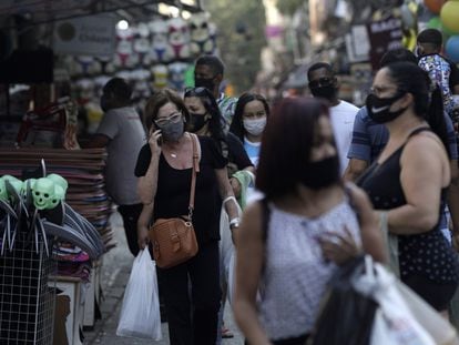 Pessoas caminham usando máscaras de proteção em uma rua de comércio popular no Rio de Janeiro.