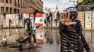 Vários manifestantes tentam atravessar as barreiras de concreto erguidas em 11 de fevereiro para impedir que civis entrem no Parlamento libanês, em Beirute.