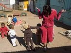 Crianças xeretam os bolsos de uma visitante em um jardim da infância de Soweto.