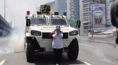 María José Castro caminha com uma bandeira da Venezuela até um blindado da Guarda Nacional Bolivariana