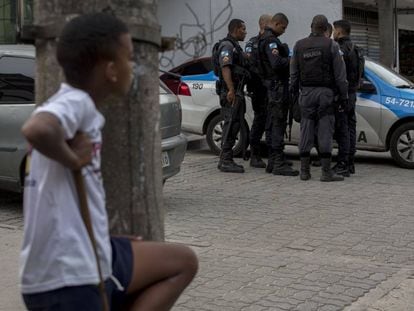 Uma criança observa um grupo de policiais na Cidade de Deus, no Rio.