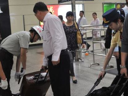 Seguranças revistam as bagagens dos passageiros na estação de trens de Guangzhou.