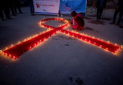 Mulheres e crianças do orfanato de recuperação para pacientes de Aids Maiti Nepal, acendem velas formando um laço vermelho, em Katmandu.