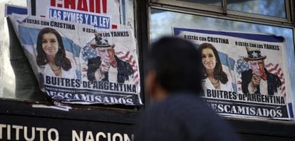Um homem passa por cartazes que falam da crise argentina, em Buenos Aires.