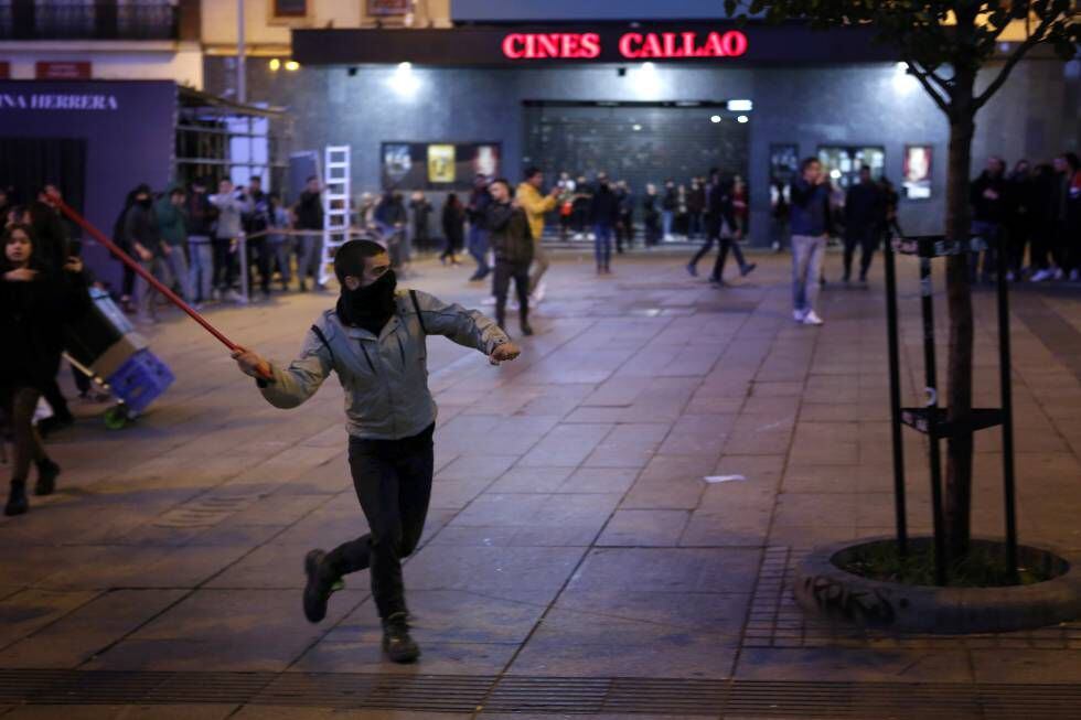 Um manifestante lança um pedaço de pau contra a força policial na praça de Callao, em Madri.