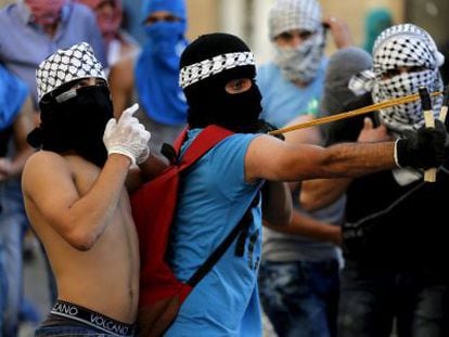 Palestino joga pedras contra a polícia israelense.