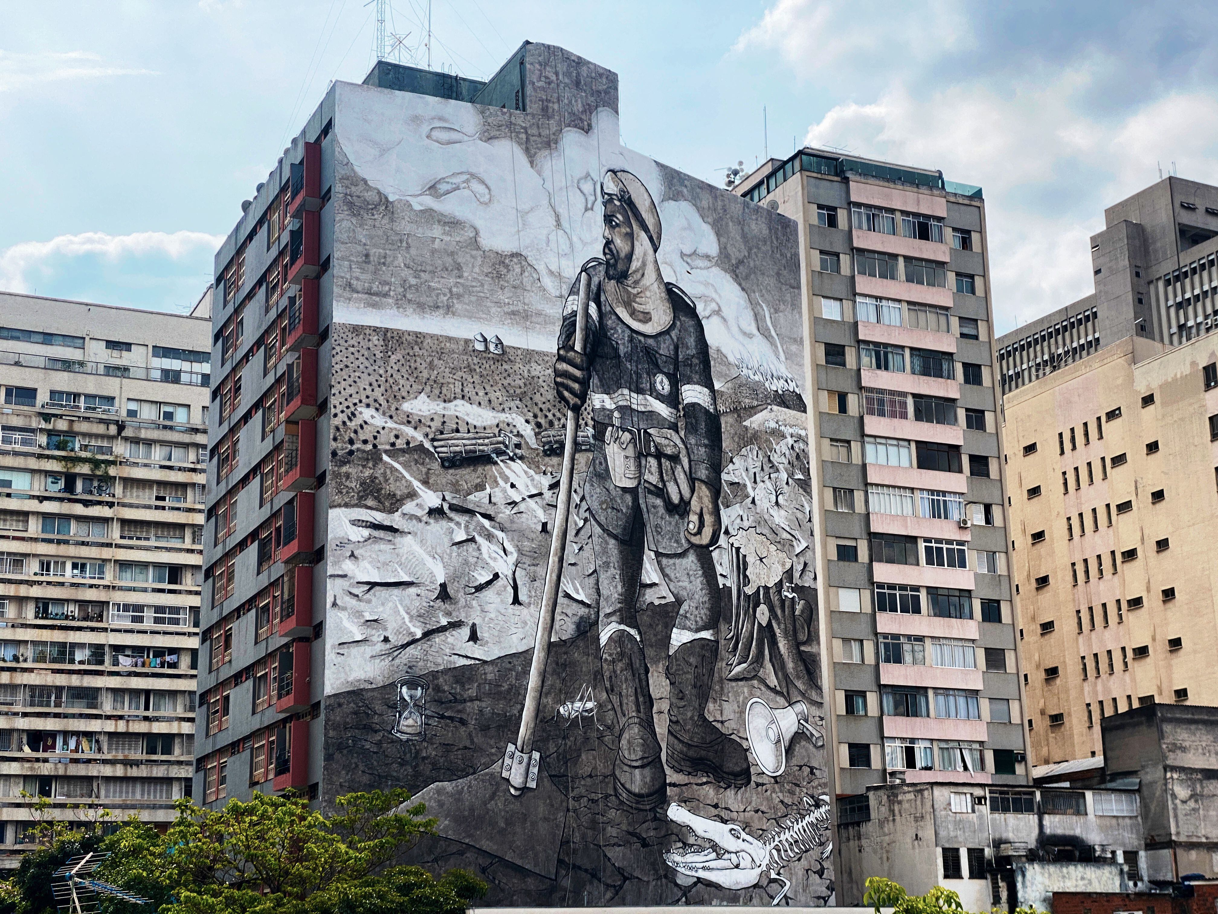 Painel em São Paulo feito com com cinzas dos incêndios nas florestas brasileiras retrata um brigadista. 