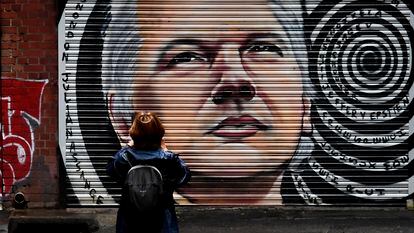 Uma mulher observa um mural com o rosto do jornalista Julian Assange nas ruas do Melbourne.