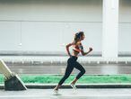 Sportswoman running in the city on sidewalk near to street