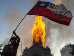 Un manifestante ondea una bandera chilena frente a una iglesia incendiada en Santiago, este domingo.