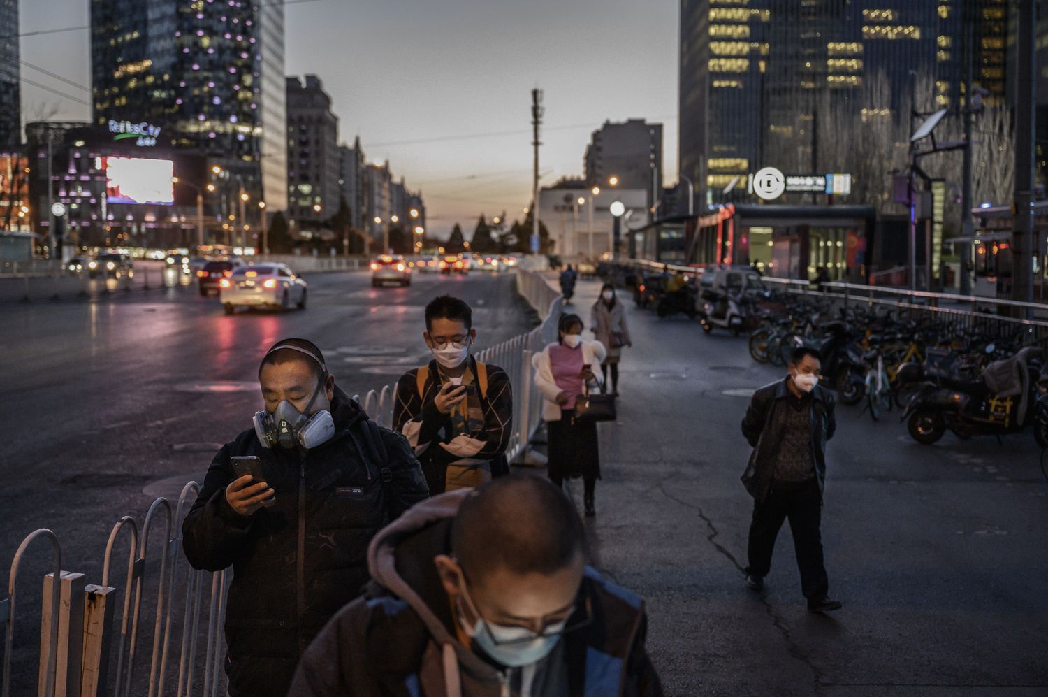 Chineses, todos de máscara, fazem fila no ponto de ônibus em Pequim, em 20 de março.