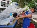 TOPSHOT - This photo taken on May 16, 2020 shows a medical worker taking a swab sample from a child to be tested for the COVID-19 coronavirus, in a street in Wuhan, in China's central Hubei province. (Photo by STR / AFP) / China OUT