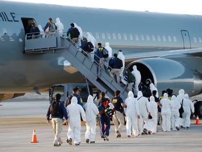 Imigrantes venezuelanos e colombianos são deportados com equipamentos de proteção contra a covid-19, no aeroporto de Iquique, Chile, nesta quarta-feira.