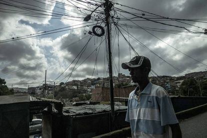 Um homem caminha em frente a uma instalação elétrica improvisada no bairro de Petares, um dos mais pobres de Caracas