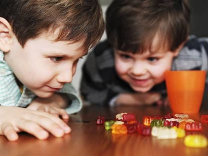 Duas crianças olhando ansiosas para doces. 