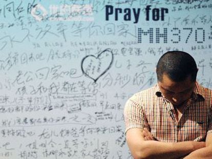 Um homem em frente a um painel com mensagens de apoio às vítimas do MH370.