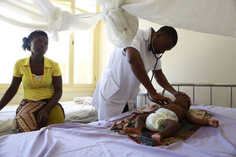 Um médico atende um bebê internado por malária em um hospital de Moçambique.