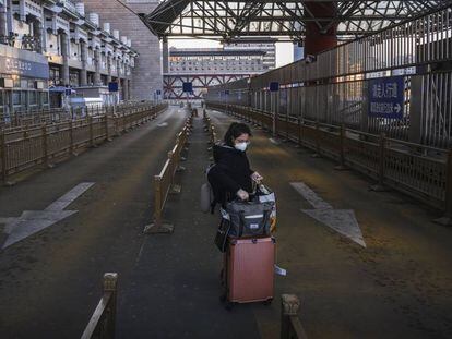 Mulher em um estacionamento de táxi vazio uma estação de trem na região oeste de Pequim.