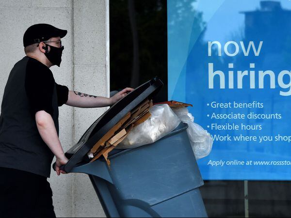 (FILES) In this file photo taken on May 14, 2020, a man wearing a face mask walks past a sign "Now Hiring" in front of a store amid the coronavirus pandemic in Arlington, Virginia. - The US economy regained 2.5 million jobs in May as coronavirus pandemic shutdowns began to ease, sending the unemployment rate falling to 13.3 percent, the Labor Department reported on June 5, 2020. (Photo by Olivier DOULIERY / AFP)