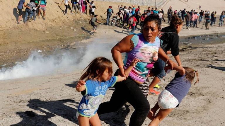 Família foge das bombas de gás lacrimogêneo próximo à fronteira entre os EUA e o México neste domingo, 25