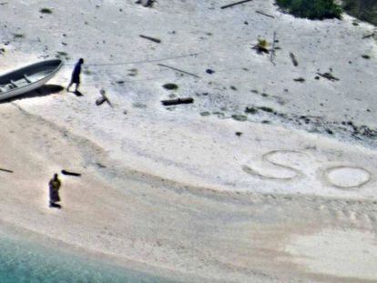 Uma foto do dia 25 de agosto que mostra os dois náufragos ao lado do SOS que desenharam na areia.