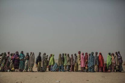 Mulheres refugiadas fazem fila em um campo de refugiados para receber um kit de higiene.