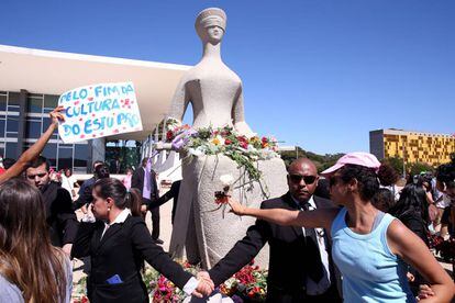 Mulheres protestam depositando flores na est&aacute;tua da Justi&ccedil;a, em Bras&iacute;lia