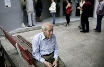 Um pensionista, sentado na fila de um caixa na Grécia.