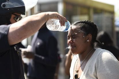 Um policial lava o rosto de uma mulher atingida por spray de pimenta ontem em Baltimore.