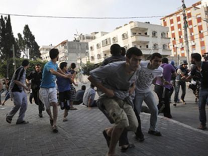 Palestinos se agacham durante bombardeio em Gaza.