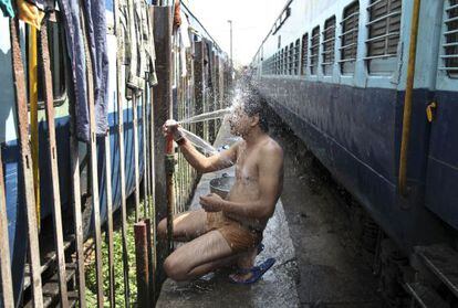 Um passageiro toma banho em uma estação de trem de Jammu, Índia.
