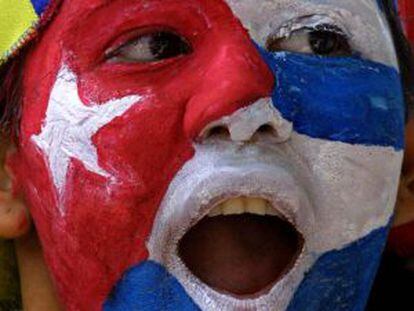 Uma mulher com a bandeira cubana pintada no rosto em frente à embaixada de Cuba na Venezuela.