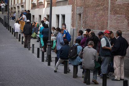 Um grupo de pessoas faz fila para entrar em um refeitório social em Madri