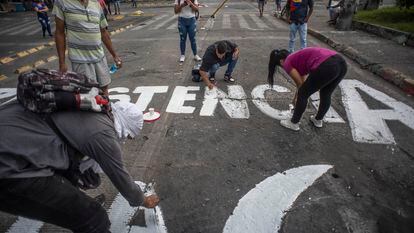 Jovens colombianos fazem pichações de protesto em uma avenida da cidade de Cali, Colômbia, em 8 de maio