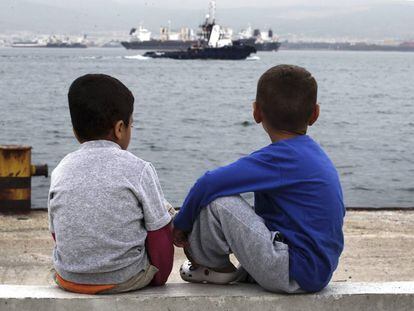 Dois meninos refugiados observam o mar, na Gr&eacute;cia.