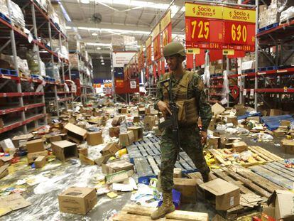 Soldado chileno monta guarda num supermercado afetado por saques, em 22 de outubro.
